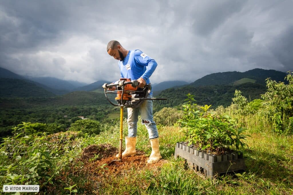 Man digging holes with auger to plant trees in Brazil's Atlantic Forest